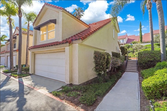25225 Avenida Tranquila, Lake Forest, CA 92630 - view of side of home featuring stucco siding, a tile roof, an attached garage, concrete driveway, and stairway