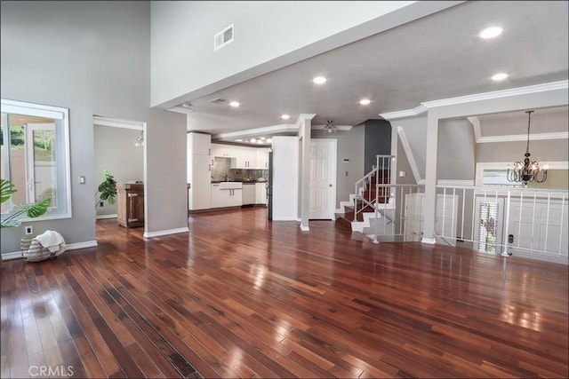 25225 Avenida Tranquila, Lake Forest, CA 92630 - unfurnished living room with a chandelier, crown molding, dark wood-style floors, a high ceiling, and stairs