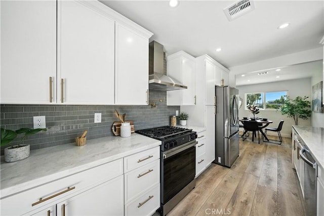 5243 Tara Pl, San Diego, CA 92117 - kitchen featuring appliances with stainless steel finishes, wall chimney range hood, white cabinets, light wood-type flooring, and recessed lighting