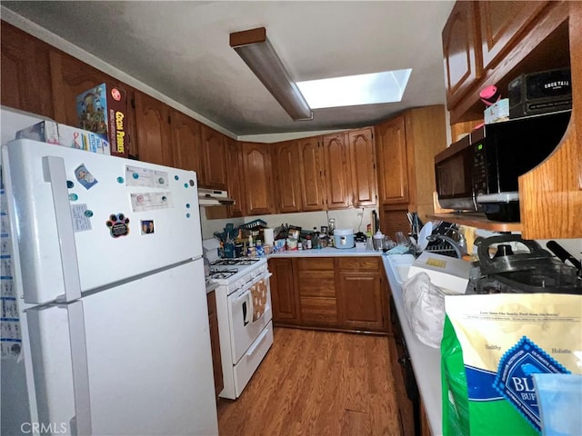 3855 Maine Ave, Baldwin Park, CA 91706 - kitchen with white appliances, light wood-style flooring, under cabinet range hood, brown cabinets, and light countertops