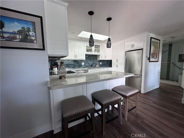 1501 Pelham Unit 127F, Seal Beach, CA 90740 - kitchen with freestanding refrigerator, a peninsula, white cabinets, and glass insert cabinets