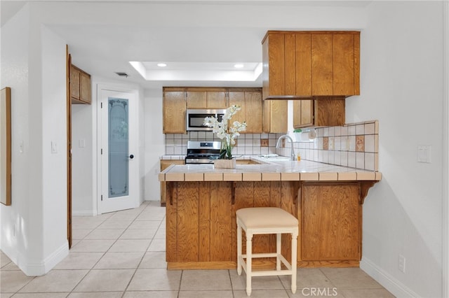 12490 Palomino Ln, Apple Valley, CA 92308 - kitchen with appliances with stainless steel finishes, brown cabinets, tile countertops, tasteful backsplash, and recessed lighting