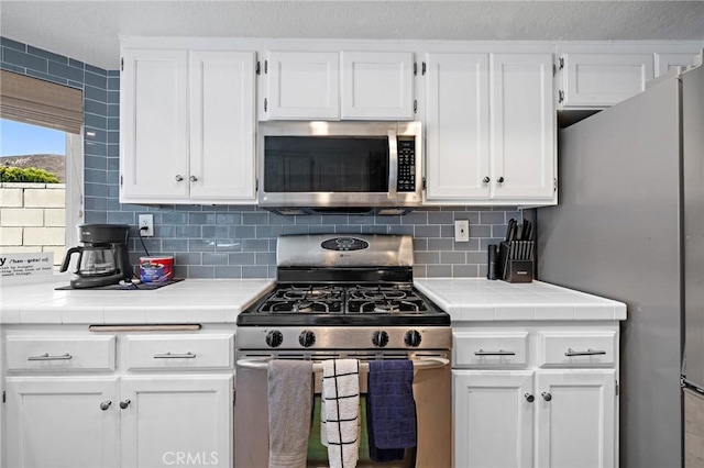 13220 February Dr, Corona, CA 92879 - kitchen with appliances with stainless steel finishes, tile countertops, white cabinetry, and backsplash