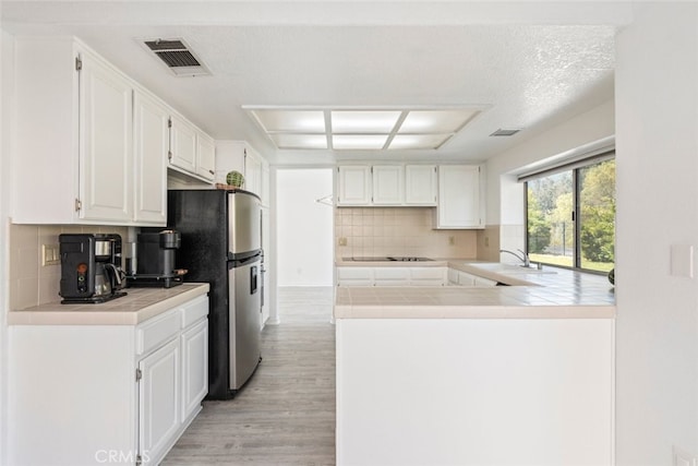 30611 Open Ct, Temecula, CA 92592 - kitchen featuring light wood-style floors, tile counters, freestanding refrigerator, white cabinets, and tasteful backsplash