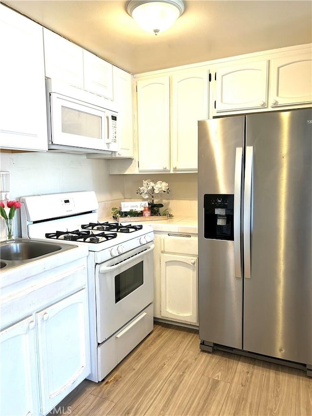 38710 10th St E Unit 12, Palmdale, CA 93550 - kitchen featuring white appliances, light countertops, light wood-style flooring, and white cabinets