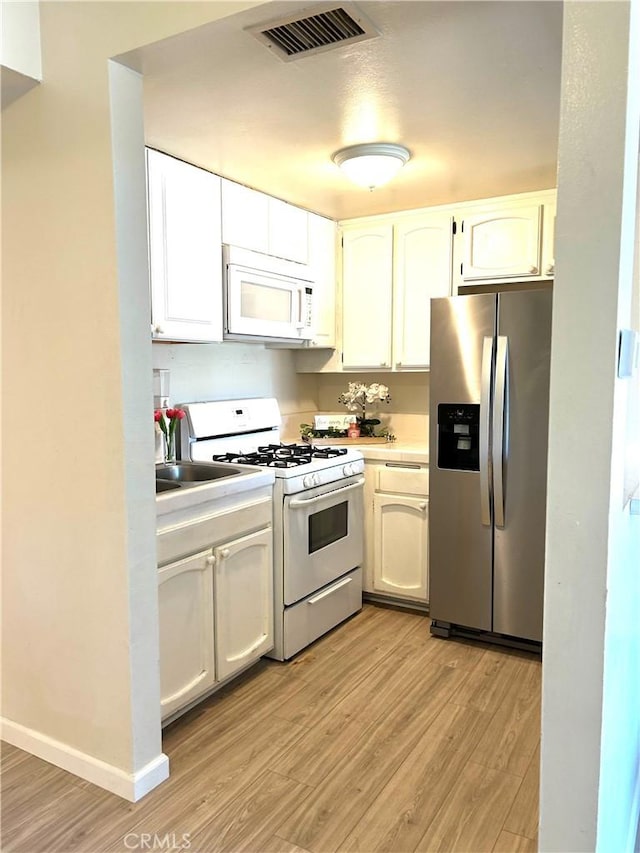 38710 10th St E Unit 12, Palmdale, CA 93550 - kitchen featuring white appliances, light wood-style floors, white cabinetry, and light countertops