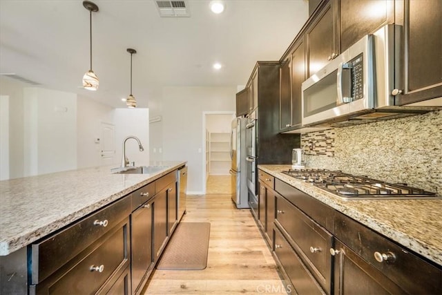 1920 Clementine St, Redlands, CA 92374 - kitchen featuring appliances with stainless steel finishes, light wood finished floors, dark brown cabinets, hanging light fixtures, and decorative backsplash