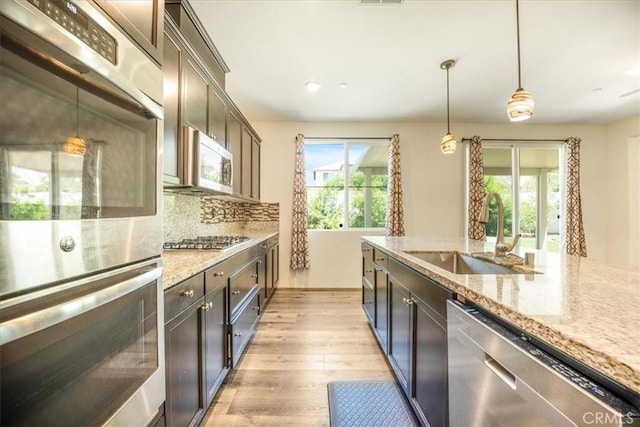 1920 Clementine St, Redlands, CA 92374 - kitchen with appliances with stainless steel finishes, light wood finished floors, light stone countertops, pendant lighting, and dark brown cabinets