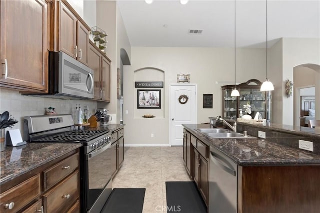 9504 Whitman Ave, Bakersfield, CA 93311 - kitchen featuring appliances with stainless steel finishes, arched walkways, backsplash, decorative light fixtures, and light tile patterned flooring