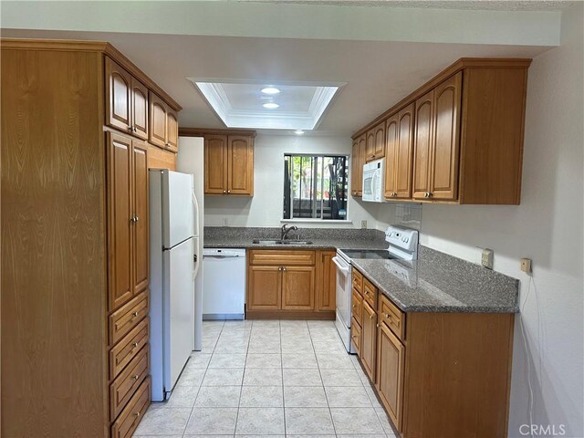 967 Calle Aragon Unit B, Laguna Woods, CA 92637 - kitchen with white appliances, a raised ceiling, brown cabinets, dark stone counters, and crown molding