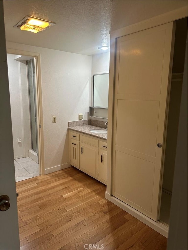 967 Calle Aragon Unit B, Laguna Woods, CA 92637 - full bathroom with vanity, wood finished floors, a textured ceiling, and a stall shower