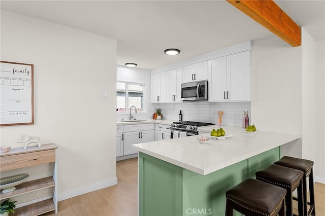 2998 N H St, San Bernardino, CA 92405 - kitchen with appliances with stainless steel finishes, light wood-style floors, a kitchen bar, decorative backsplash, and a peninsula