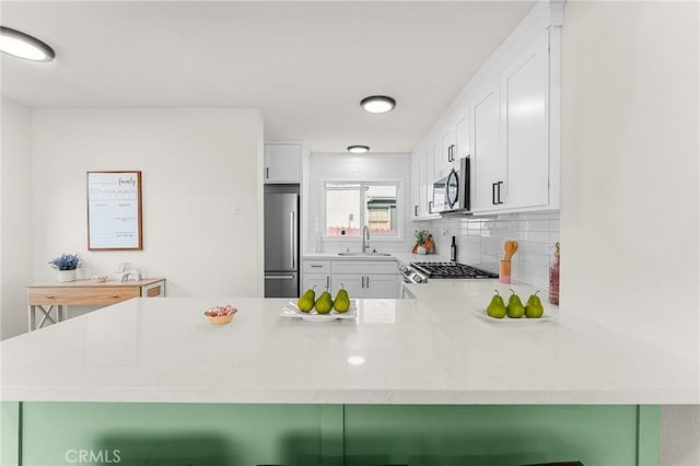 2998 N H St, San Bernardino, CA 92405 - kitchen featuring appliances with stainless steel finishes, a peninsula, light countertops, white cabinets, and backsplash