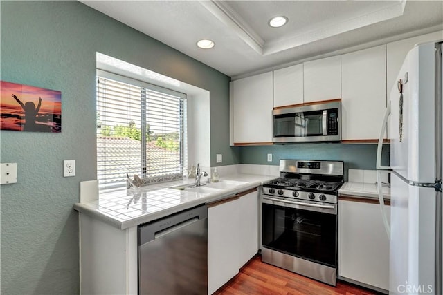 94 Cinnamon Teal, Aliso Viejo, CA 92656 - kitchen featuring stainless steel appliances, a textured wall, tile countertops, a tray ceiling, and white cabinets