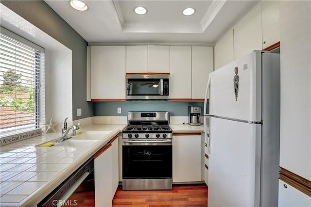 94 Cinnamon Teal, Aliso Viejo, CA 92656 - kitchen with stainless steel appliances, tile counters, a raised ceiling, dark wood finished floors, and recessed lighting