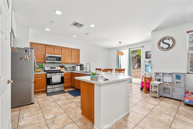 3381 Evening Mist Ln, Perris, CA 92571 - kitchen featuring appliances with stainless steel finishes, a peninsula, light countertops, light tile patterned floors, and backsplash