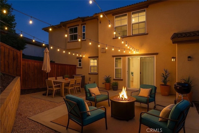 3381 Evening Mist Ln, Perris, CA 92571 - back of house at twilight with an outdoor fire pit, stucco siding, a patio area, and a tiled roof