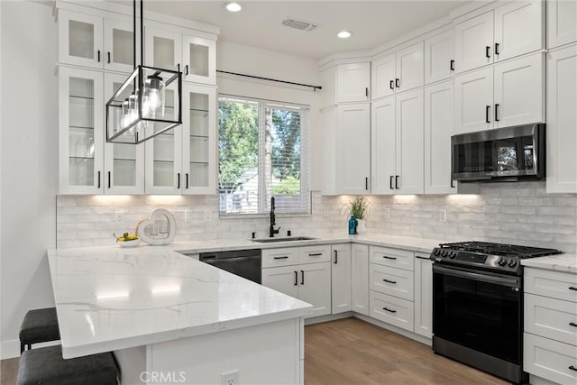 5790 Fickett Ln, Paradise, CA 95969 - kitchen featuring appliances with stainless steel finishes, a peninsula, white cabinetry, a breakfast bar area, and light wood-style floors