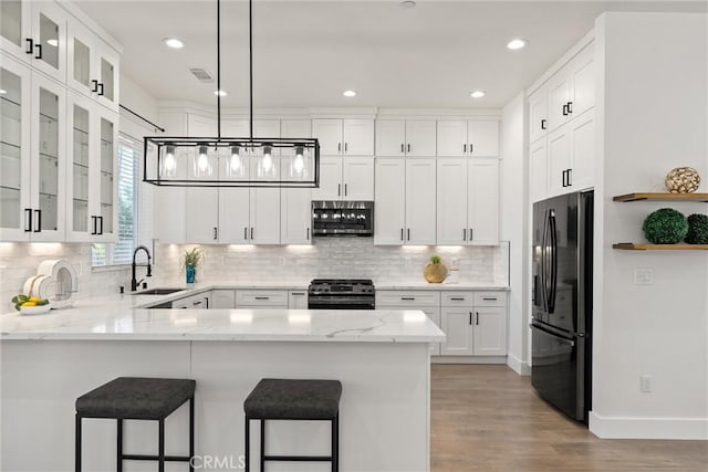 5790 Fickett Ln, Paradise, CA 95969 - kitchen with black fridge, gas range oven, a peninsula, stainless steel microwave, and white cabinetry