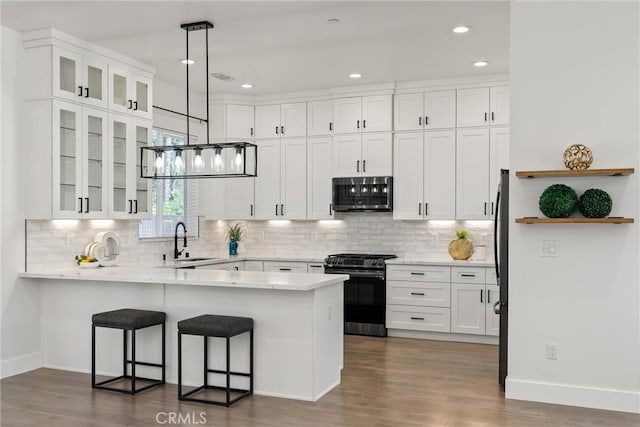 5790 Fickett Ln, Paradise, CA 95969 - kitchen with appliances with stainless steel finishes, a peninsula, white cabinets, a kitchen breakfast bar, and wood finished floors
