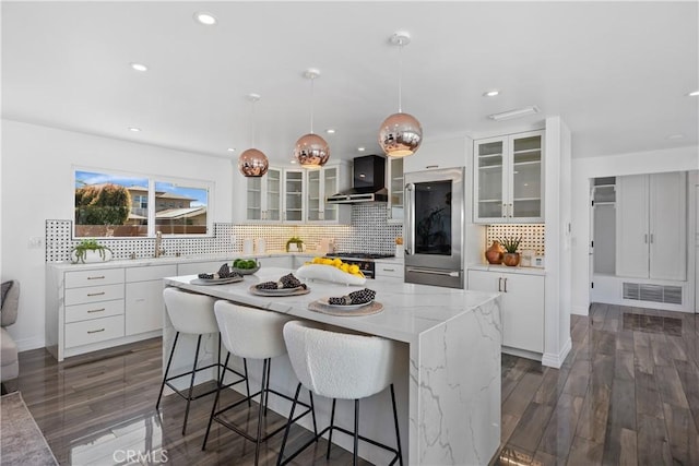 496 E 16th, Costa Mesa, CA 92627 - kitchen with wall chimney range hood, a kitchen island, tasteful backsplash, white cabinetry, and a breakfast bar area