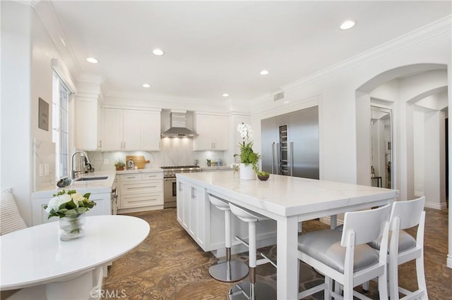 33 Renata, Newport Coast, CA 92657 - kitchen featuring premium appliances, wall chimney range hood, recessed lighting, a kitchen breakfast bar, and a center island