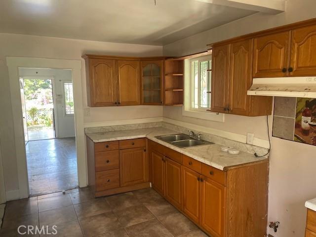 1153 Isabel St, Los Angeles, CA 90065 - kitchen featuring under cabinet range hood, brown cabinets, light countertops, and glass insert cabinets