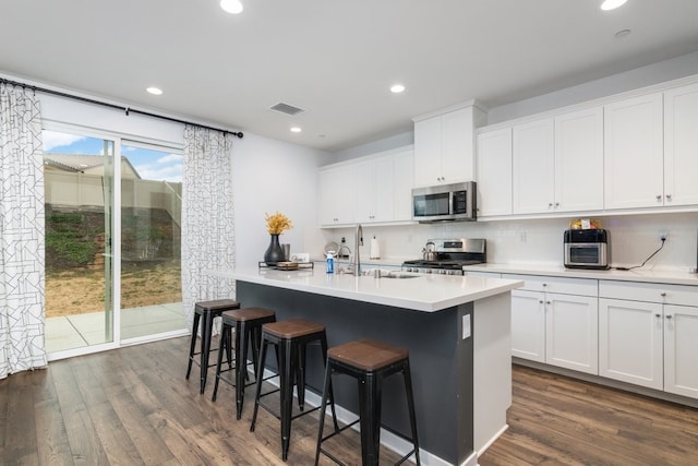 36961 Buccella Ln, Beaumont, CA 92223 - kitchen with appliances with stainless steel finishes, dark wood-style floors, a breakfast bar area, a center island with sink, and decorative backsplash