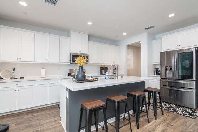 36961 Buccella Ln, Beaumont, CA 92223 - kitchen featuring stainless steel appliances, a breakfast bar, decorative backsplash, light wood-style floors, and white cabinets
