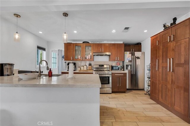 9707 Foothill Blvd, Sylmar, CA 91342 - kitchen featuring stainless steel appliances, under cabinet range hood, pendant lighting, brown cabinets, and recessed lighting