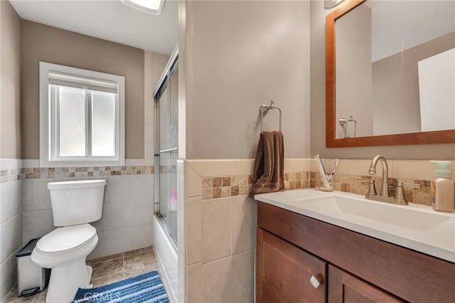 9707 Foothill Blvd, Sylmar, CA 91342 - full bathroom featuring tile walls, vanity, tile patterned floors, shower / bath combination with glass door, and a wainscoted wall