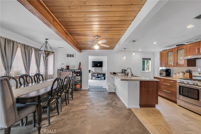 9707 Foothill Blvd, Sylmar, CA 91342 - kitchen with stainless steel range with gas cooktop, brown cabinets, glass insert cabinets, light countertops, and under cabinet range hood