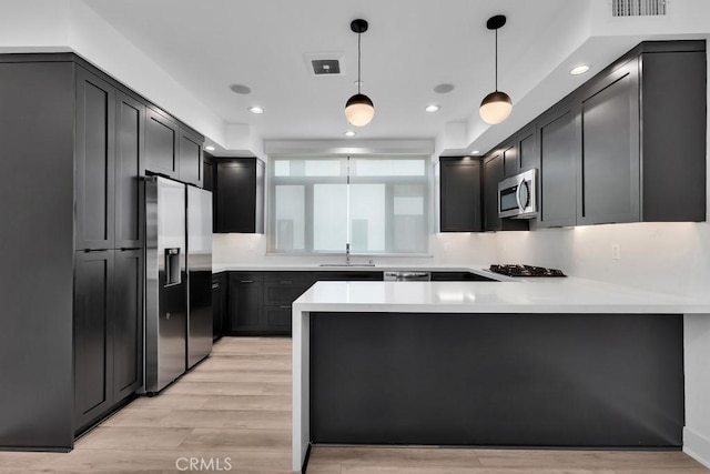 11304 Victory Blvd, North Hollywood, CA 91606 - kitchen with appliances with stainless steel finishes, a peninsula, pendant lighting, light countertops, and light wood-style flooring