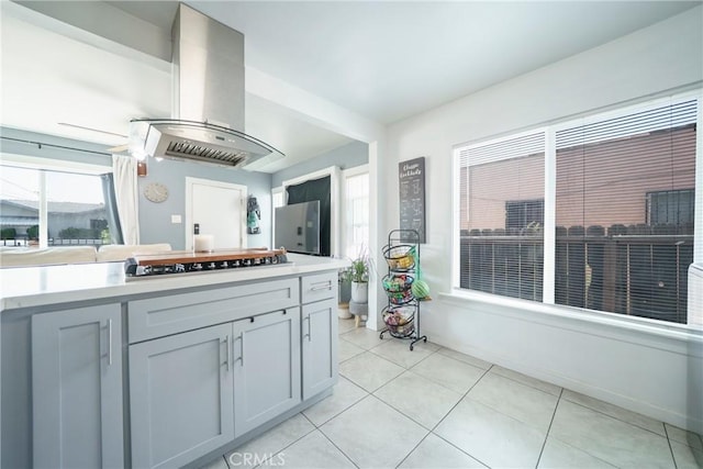 8217 Towne Ave, Los Angeles, CA 90003 - kitchen with black stovetop, exhaust hood, light countertops, light tile patterned floors, and freestanding refrigerator