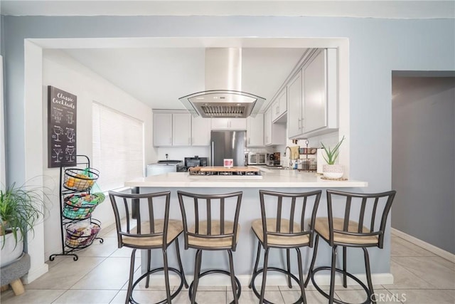 8217 Towne Ave, Los Angeles, CA 90003 - kitchen with ventilation hood, stainless steel fridge, light countertops, a peninsula, and a breakfast bar area