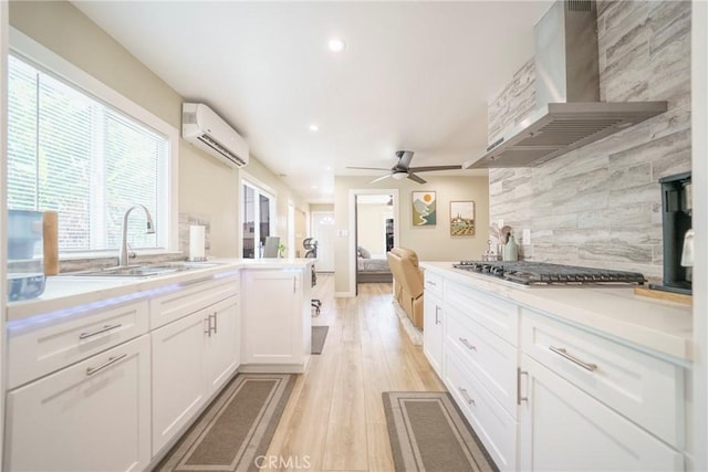 8217 Towne Ave, Los Angeles, CA 90003 - kitchen featuring wall chimney range hood, a wall mounted air conditioner, stainless steel gas cooktop, ceiling fan, and decorative backsplash