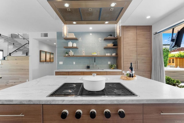 5530 Candlelight Dr, La Jolla, CA 92037 - kitchen with open shelves, brown cabinets, stainless steel gas cooktop, exhaust hood, and backsplash