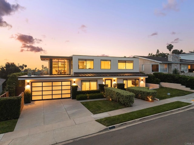 5530 Candlelight Dr, La Jolla, CA 92037 - view of front facade featuring a standing seam roof, concrete driveway, an attached garage, a yard, and stucco siding