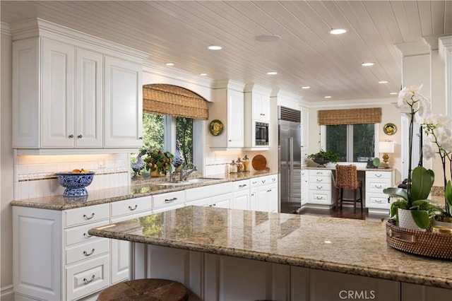 126 Monarch Bay, Dana Point, CA 92629 - kitchen with built in appliances, white cabinets, recessed lighting, light stone counters, and a kitchen bar