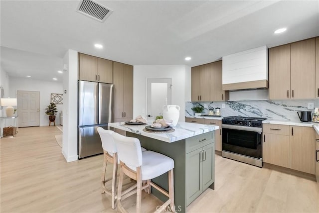 46079 Galaxy Ct, Temecula, CA 92592 - kitchen featuring appliances with stainless steel finishes, light wood-type flooring, a kitchen bar, a kitchen island, and recessed lighting