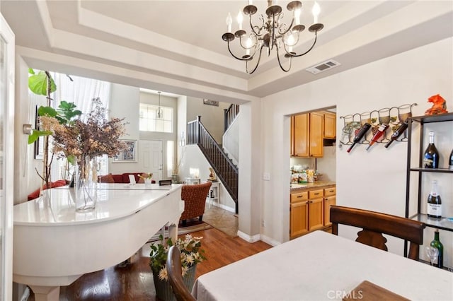 25880 Jumano Dr, Moreno Valley, CA 92551 - dining room featuring a tray ceiling, stairs, wood finished floors, and a chandelier
