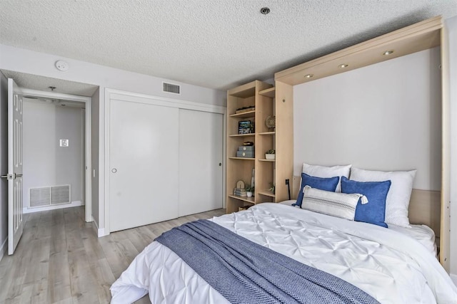 1508 Circa Del Lago Blvd Unit B204, San Marcos, CA 92078 - bedroom featuring light wood-style flooring, a closet, and a textured ceiling