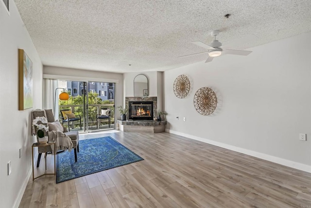 1508 Circa Del Lago Blvd Unit B204, San Marcos, CA 92078 - living room featuring a textured ceiling, wood finished floors, a ceiling fan, and a high end fireplace