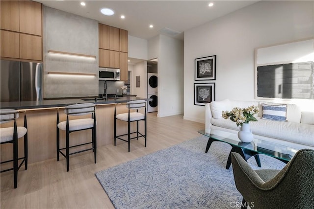 18852 Collins St, Tarzana, CA 91356 - living area featuring stacked washer and clothes dryer, light wood-style floors, and recessed lighting