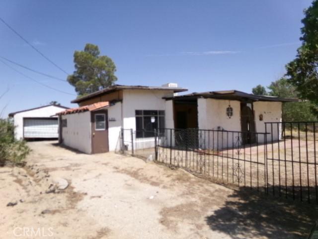 34915 Cedar Rd, Barstow, CA 92311 - view of front facade featuring stucco siding, a garage, and an outbuilding