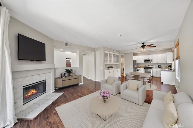 45114 Via Quivera, Temecula, CA 92592 - living area with a tiled fireplace, a ceiling fan, and dark wood finished floors