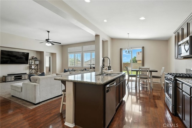 31969 Frontier Manor St, Menifee, CA 92584 - kitchen featuring stainless steel appliances, light stone counters, dark wood-style flooring, an island with sink, and dark brown cabinetry