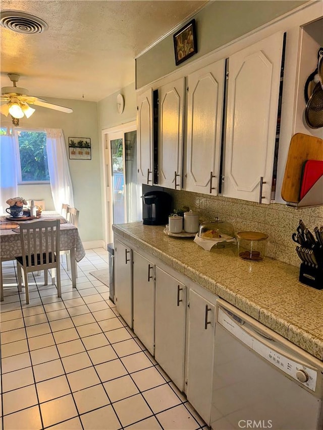9778 Sharon Ave, Riverside, CA 92503 - kitchen with white dishwasher, a ceiling fan, white cabinetry, light tile patterned floors, and decorative backsplash
