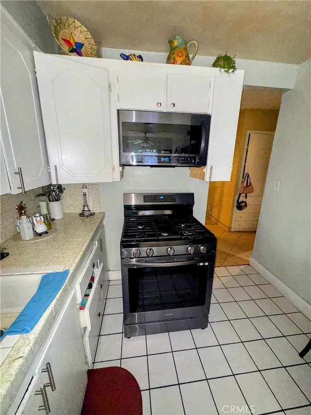 9778 Sharon Ave, Riverside, CA 92503 - kitchen featuring stainless steel appliances, white cabinets, light tile patterned floors, tile counters, and a ceiling fan
