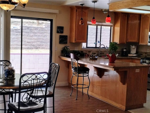 13205 Santa Lucia Rd, Atascadero, CA 93422 - kitchen featuring stainless steel gas range, a peninsula, dark countertops, a breakfast bar area, and brown cabinets